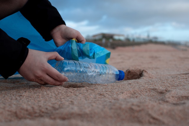 A volunteer picks up and disposes of trash on a beach. 