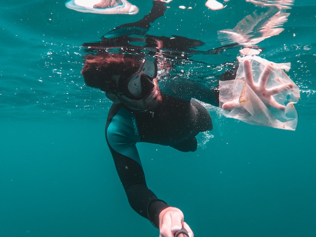 A diver picks up trash floating in the ocean