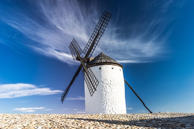 A windmill attached to a white building, the clear blue sky in the background