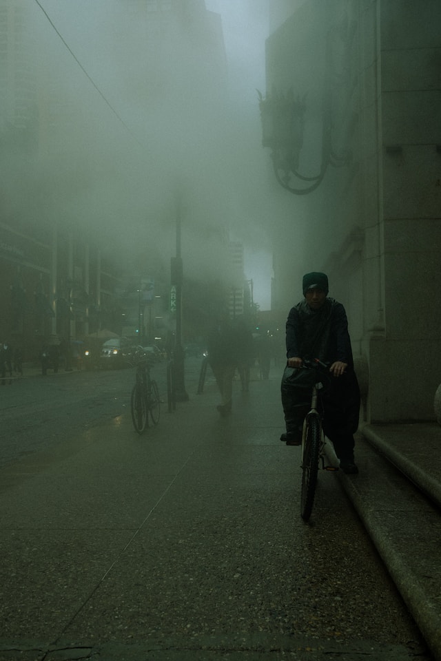 Person on a bicycle in a city that is covered in smog
