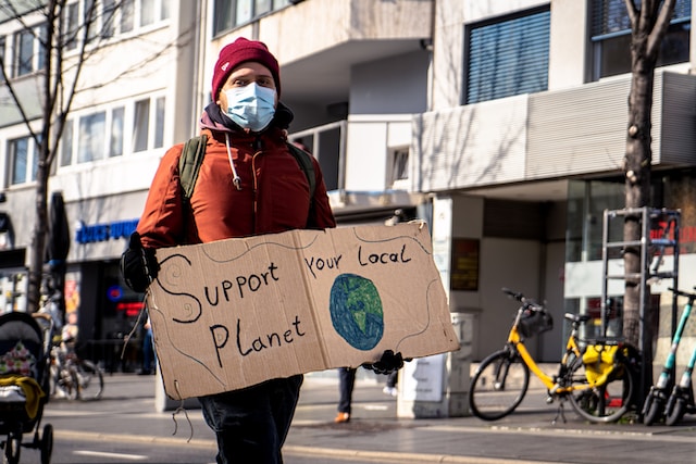 Person holding a cardboard sign at a climate protest