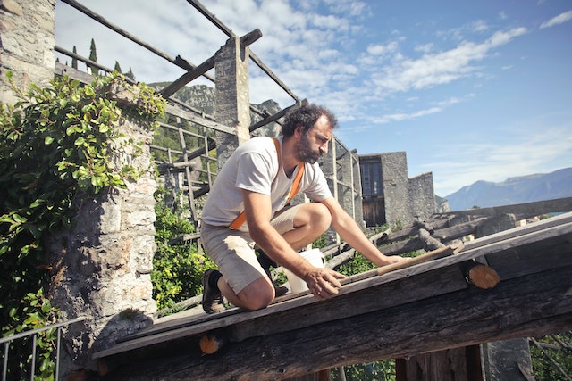 Guy fixing the roof of a wooden structure