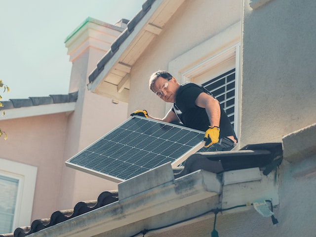 Person installing solar panels to a house